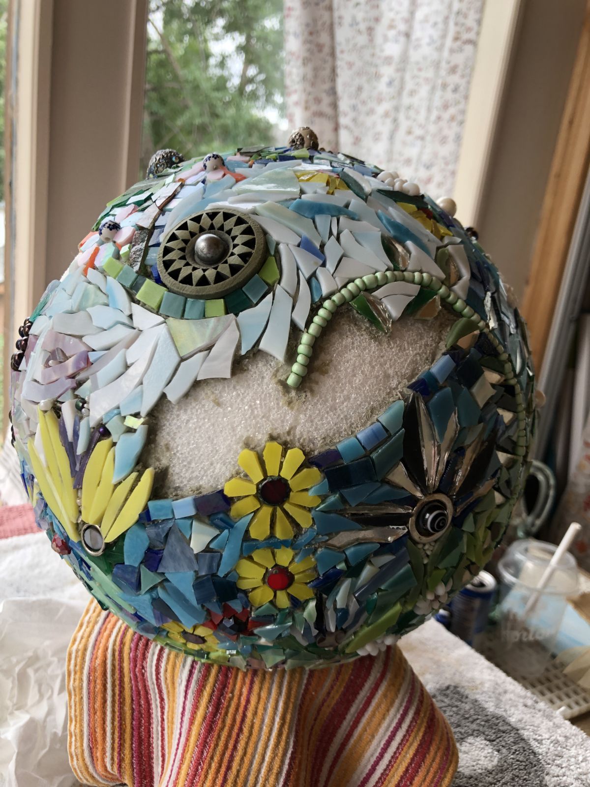A styrofoam ball partly covered in mosaic flowers and greenery.