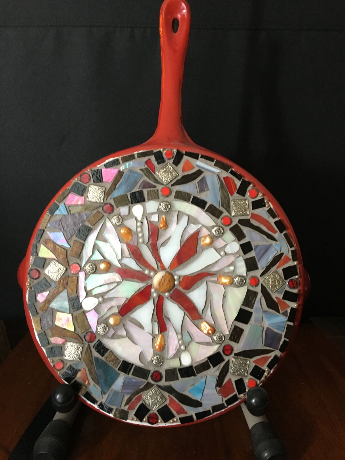 A red frying pan with a mosaic on the bottom.
