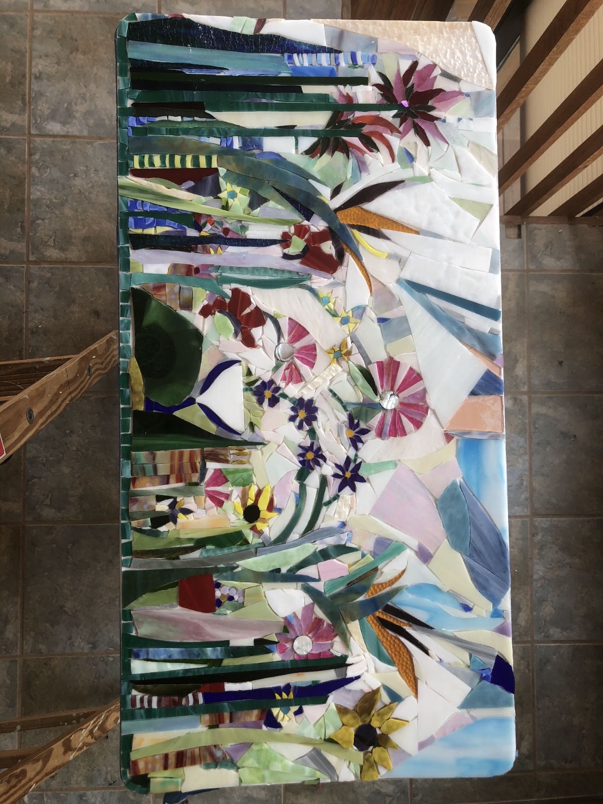 A table partly covered in mosaic flowers and greenery.